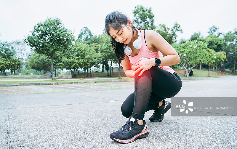 膝盖疼痛。运动损伤，女性在户外运动时膝盖疼痛。跑步运动中女性膝盖受伤图片素材