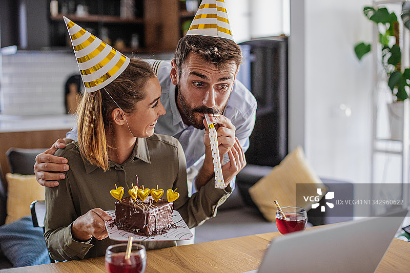 年轻夫妇在家中通过视频通话与朋友庆祝生日图片素材