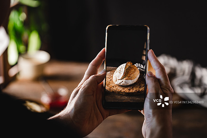 女人在厨房拍摄新鲜出炉的酵母面包图片素材