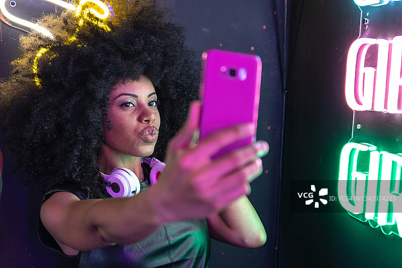 一位非洲-加勒比女人和旁边的霓虹灯自拍图片素材