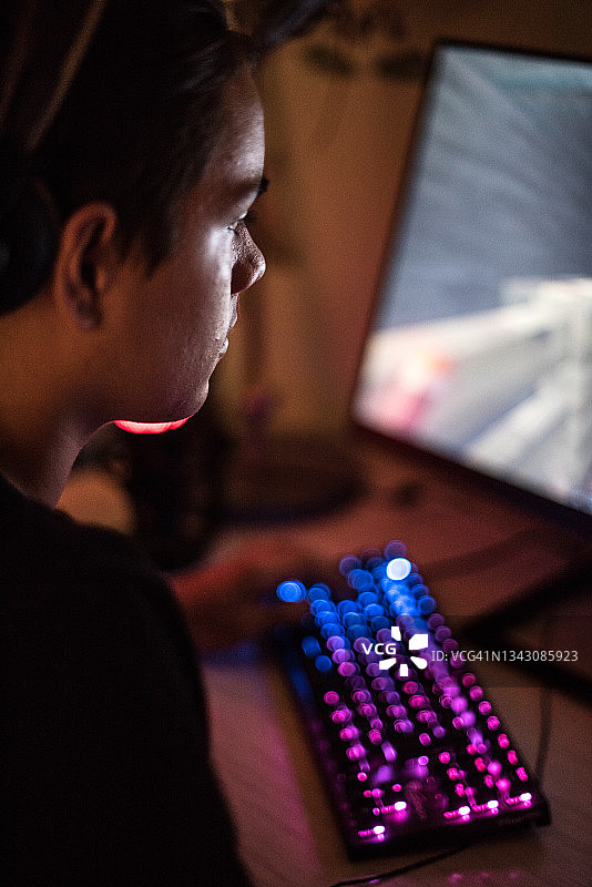 青少年男孩戴着耳机在电脑上玩多人视频游戏图片素材