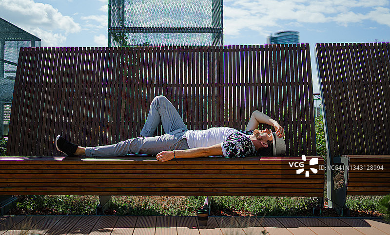 夏季小镇户外长椅上休息的年轻男子肖像图片素材