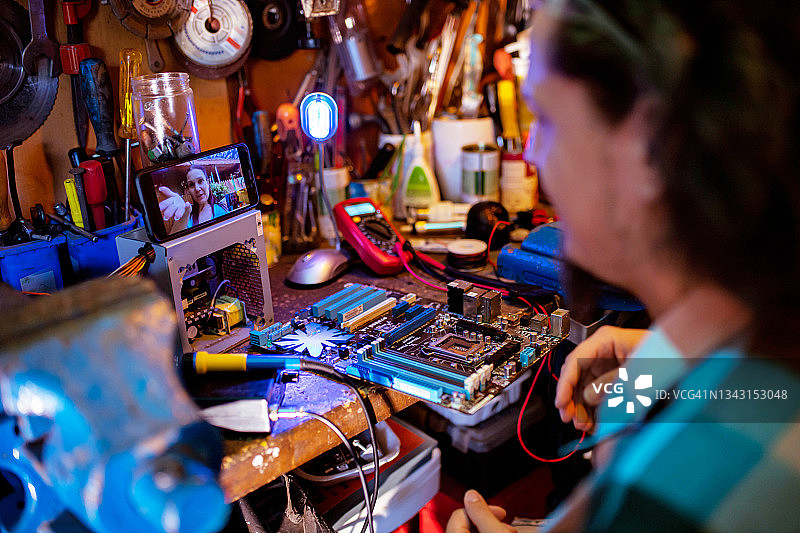 男人在他的维修店通过视频通话授课图片素材