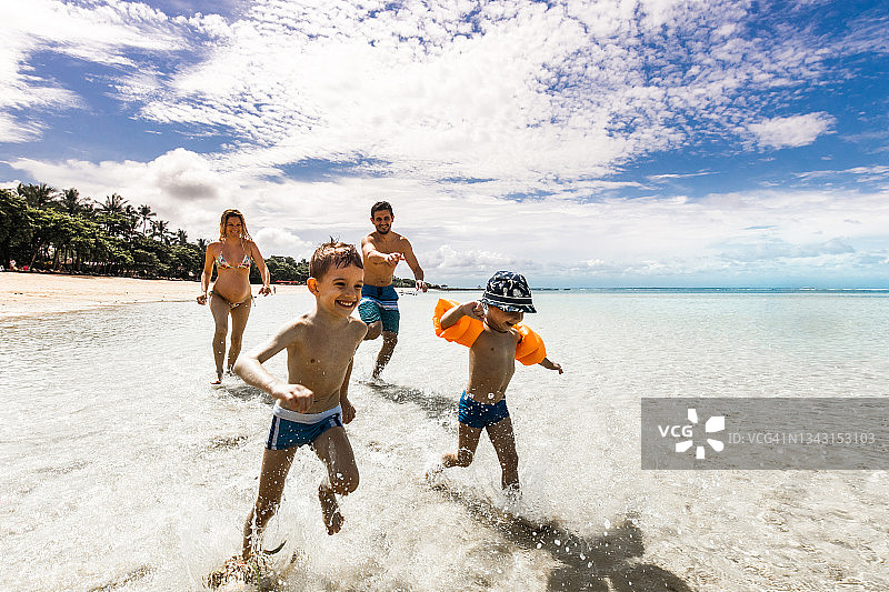 在海滩上逃离父母的可爱男孩们图片素材