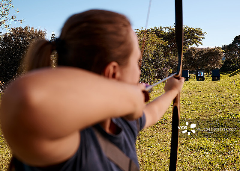 一名女弓箭手在射箭场练习的背影图片素材