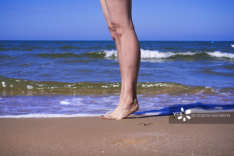 在水边踮起脚尖的女人腿部图片素材
