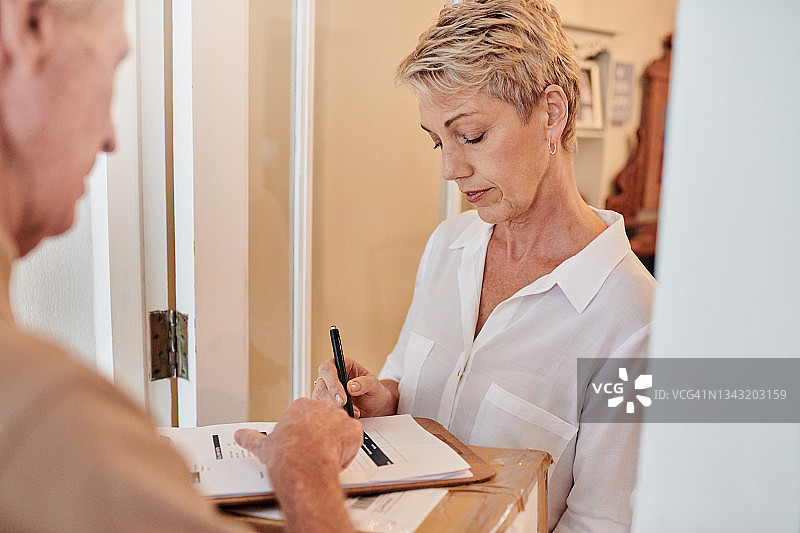 有魅力的老年妇女在家中收到男快递员的送货图片素材