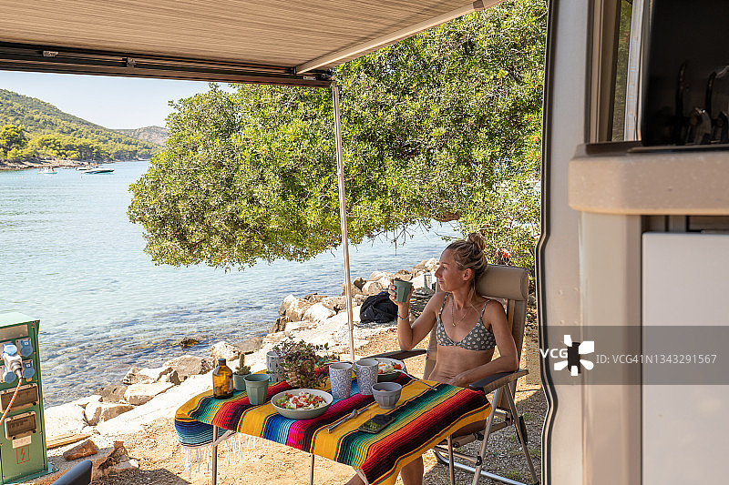 女人在海滩边的车里享用午餐图片素材