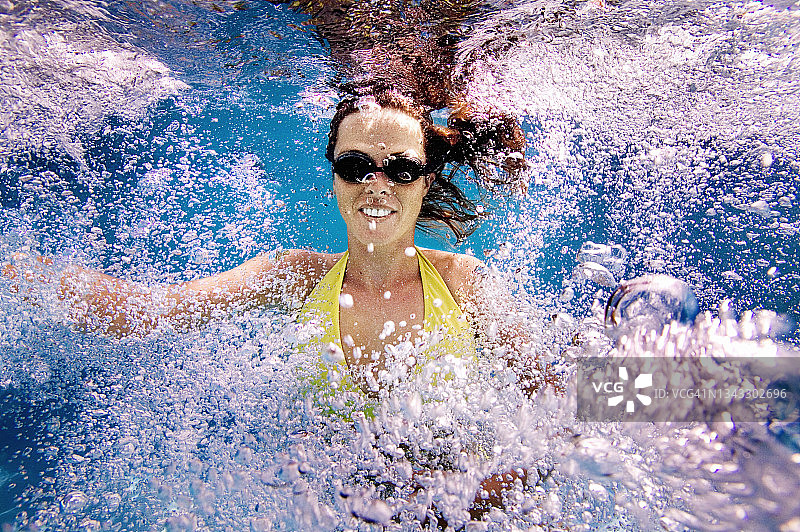 在蓝色海水中游泳的年轻女人图片素材