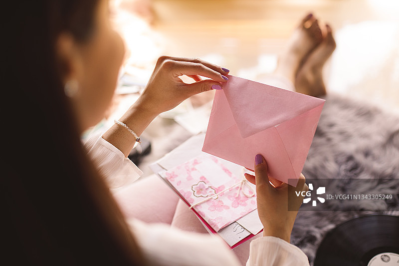 打开粉色情书信封的年轻女人图片素材