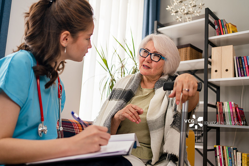 在covid-19大流行期间，医生上门拜访一位老年妇女图片素材