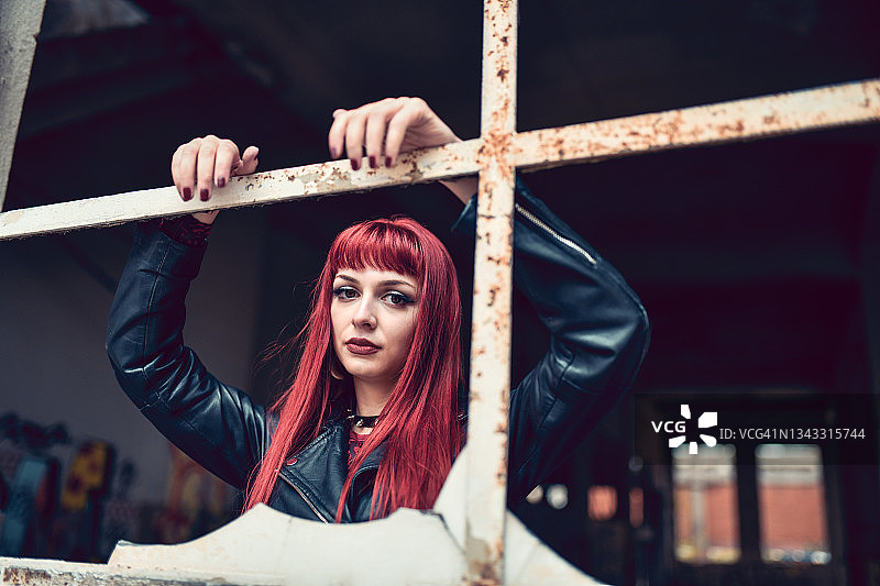 红发哥特风女子倚靠在废弃建筑的窗框上图片素材