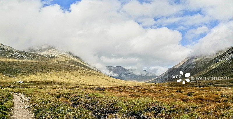 阳光明媚的峡谷中通往山间小屋的路径：凯恩戈姆山，苏格兰高地图片素材