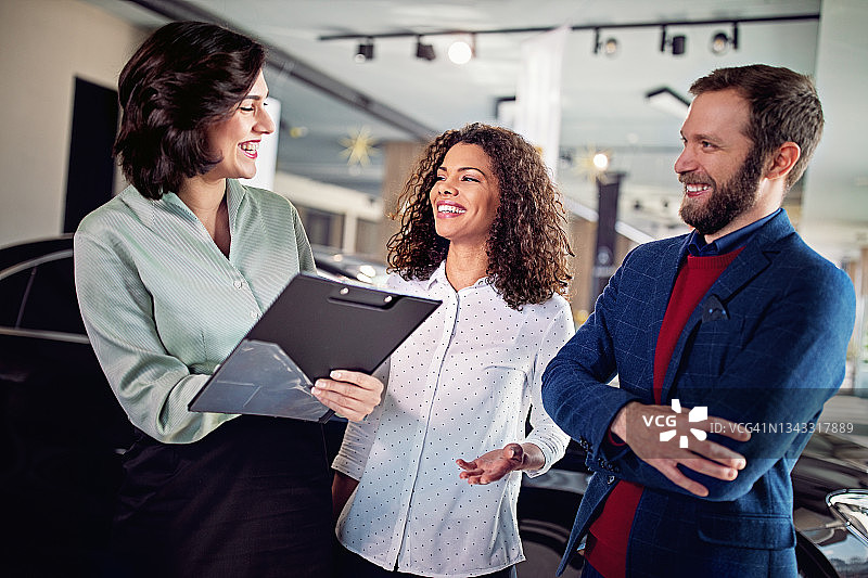 汽车经销商在展厅向一对夫妇介绍汽车图片素材