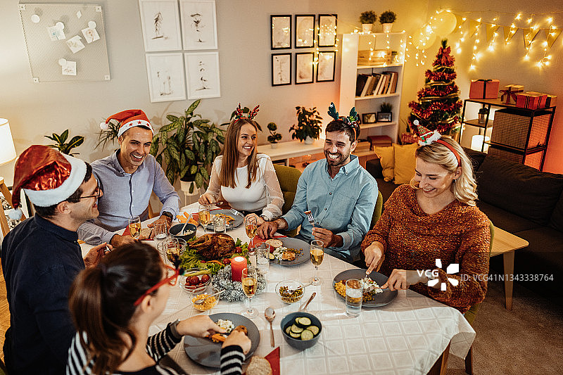 朋友们在家庆祝圣诞节，人们乔装打扮吃晚餐图片素材