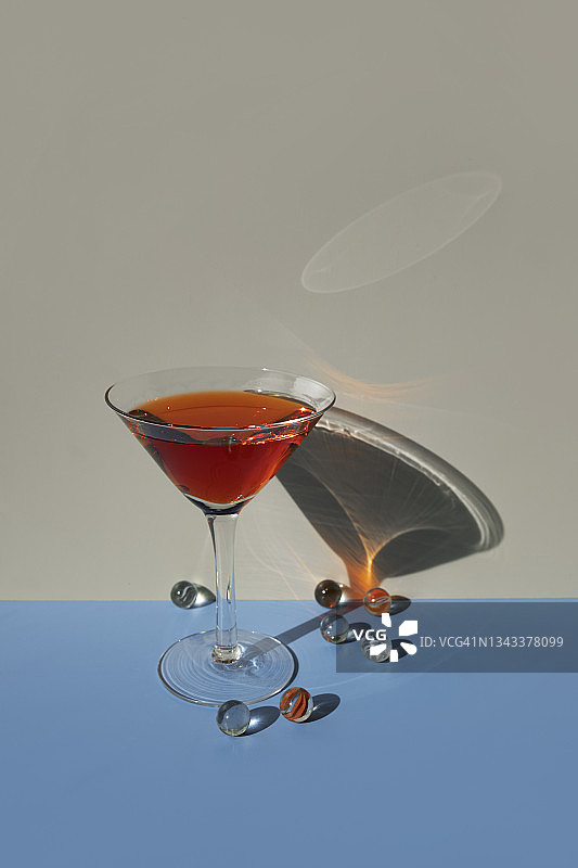 蓝色米色背景上的红色马提尼酒杯与玻璃弹珠图片素材