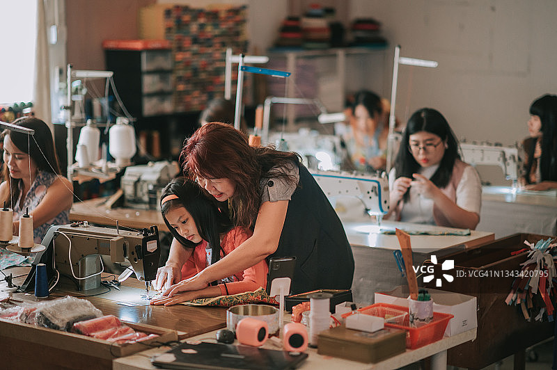 教学生缝纫技术的亚洲成熟女裁缝图片素材