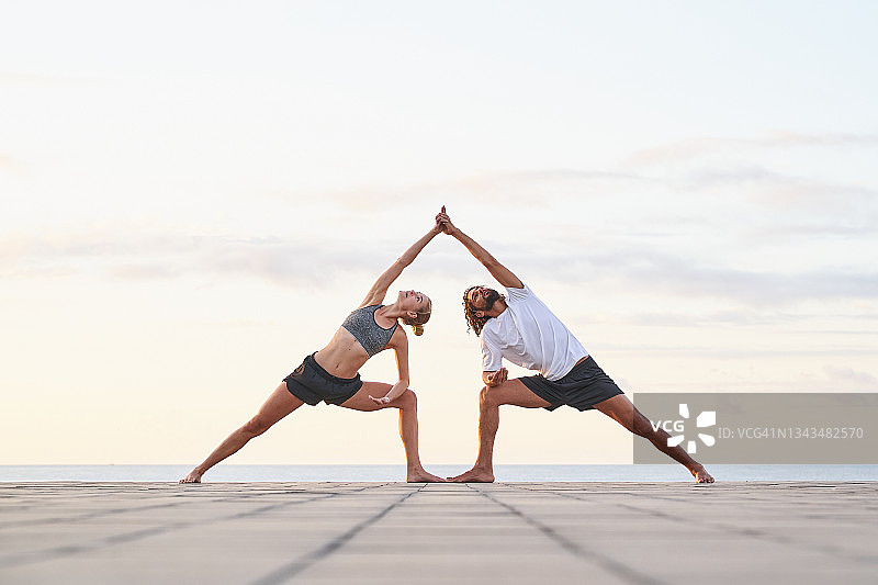 男女手牵手仰望天空做瑜伽图片素材