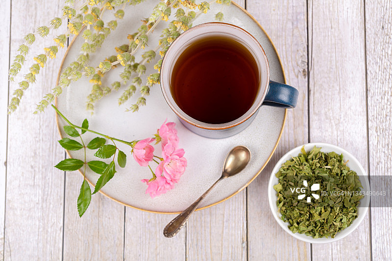 绿茶或草药茶，含茶杯、盘子和干草药图片素材