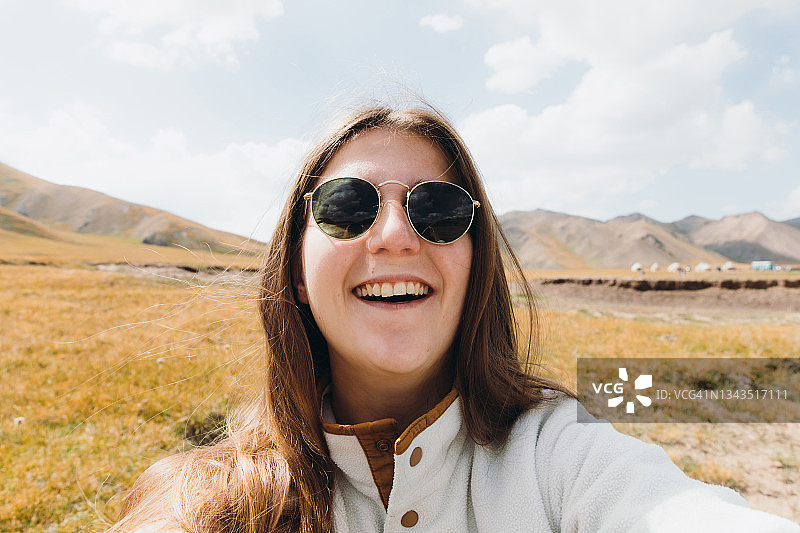 快乐的女旅行者在中亚风景秀丽的偏远山谷中自拍图片素材