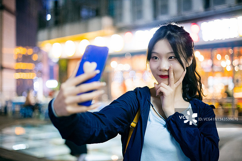 年轻亚洲女孩在城市夜晚户外自拍图片素材