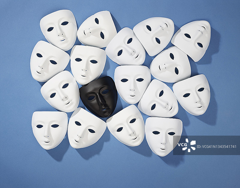 蓝色背景上围绕着一个黑色面具的多个黑色面具图片素材