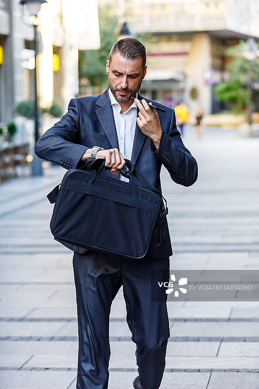 在城市街道上边走边用手机的年轻商人图片素材