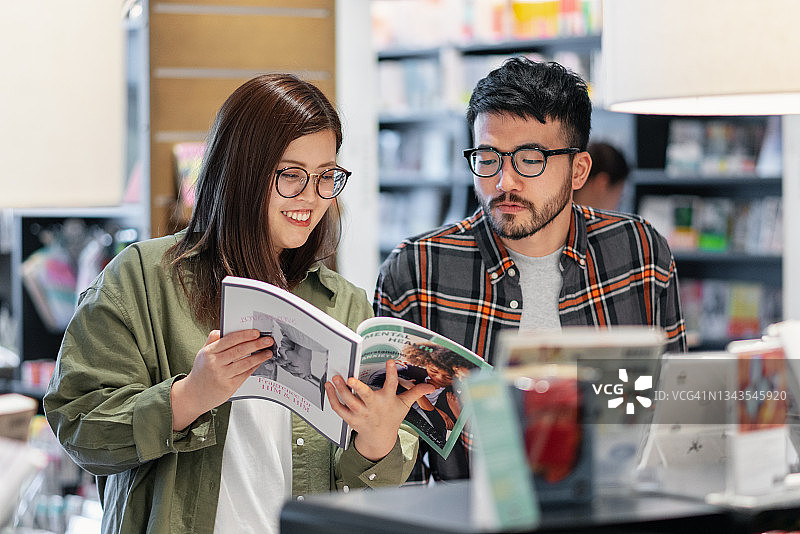 年轻夫妇一起在书店看杂志图片素材
