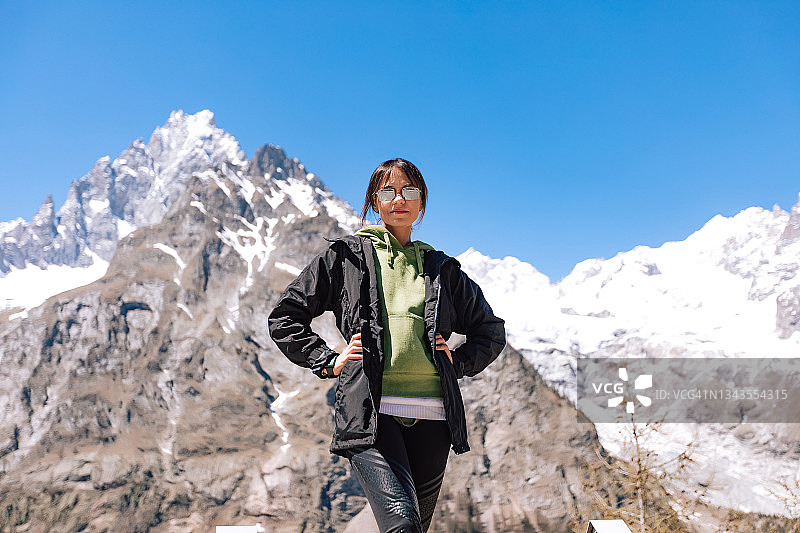 戴太阳镜在山区徒步的年轻女子户外肖像，自然风光旅行概念摄影图片素材