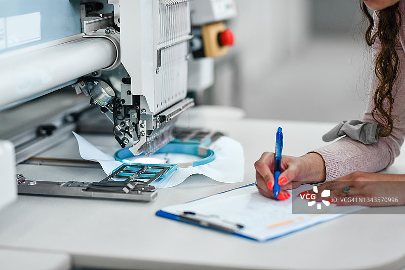 纺织女工记录精密缝纫机的工作图片素材