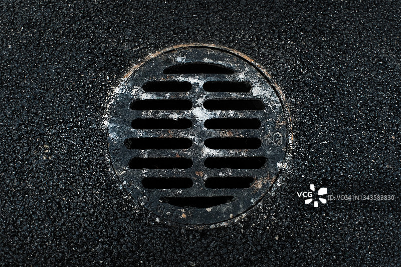 乡间或城市沥青路面上的雨水井盖图片素材