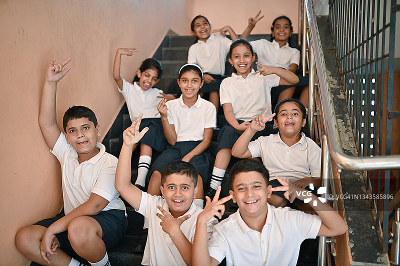 微笑的小学生坐在学校楼梯上合影图片素材