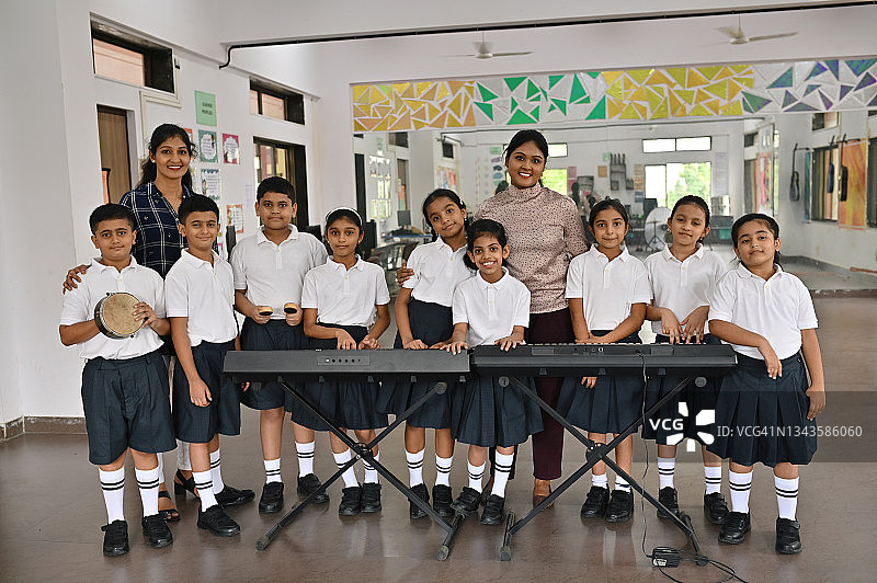 音乐室里拿着键盘乐器的学生和老师的肖像图片素材