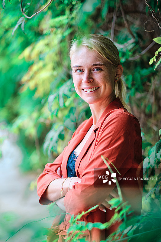 微笑的商务女性在绿植附近交叉双臂摆姿势图片素材