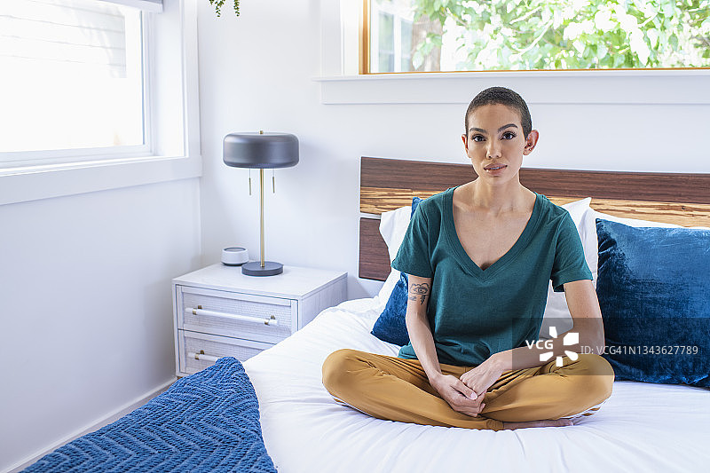 年轻女人在床上盘腿而坐图片素材