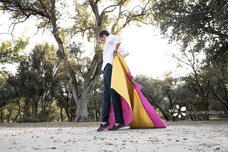 侧视图：年轻斗牛士拿着粉色斗篷图片素材