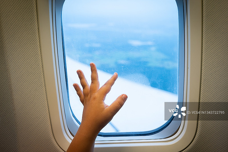 孩子在飞行中将手放在飞机窗户上图片素材