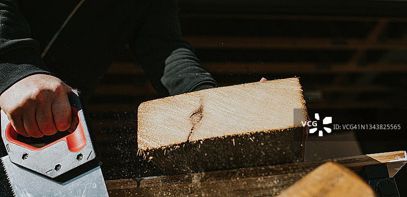 男人用手锯劈开一块厚木头图片素材