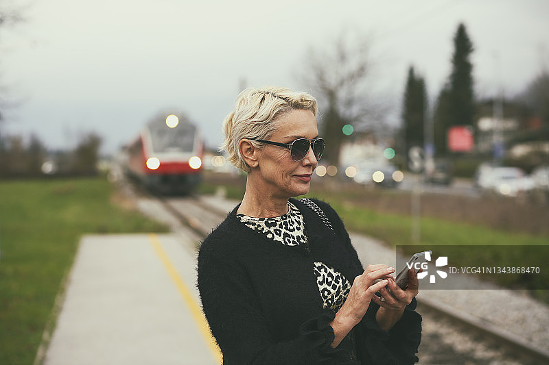 中年妇女在火车站使用手机图片素材