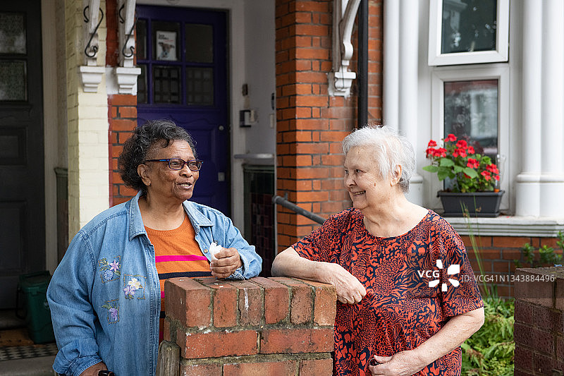 两位老朋友和邻居在屋外聊天图片素材