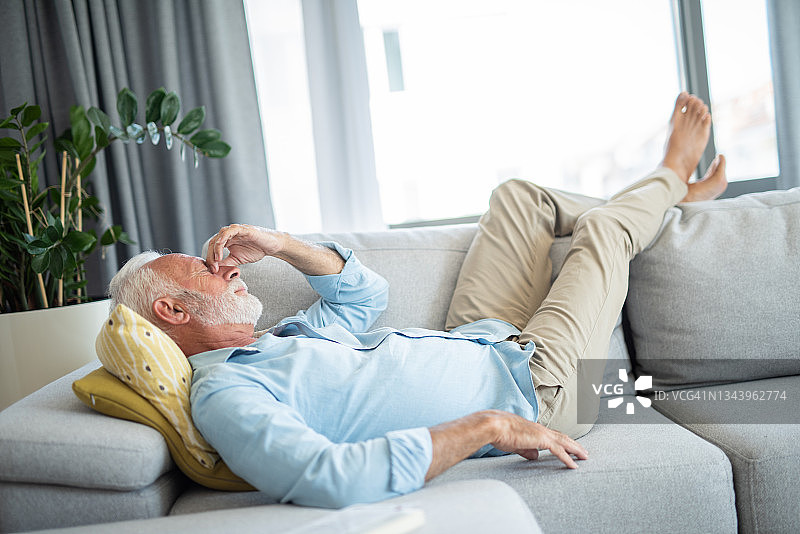 年长的男人躺在沙发上头痛图片素材
