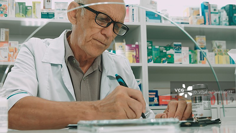 药房里的男性药剂师正在开药方图片素材