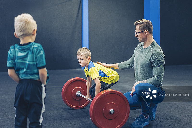 教练协助男孩进行姿势锻炼图片素材
