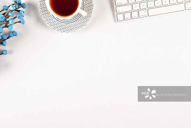 办公室创意办公桌与蓝色花朵、绿茶、电脑键盘白色背景图片素材
