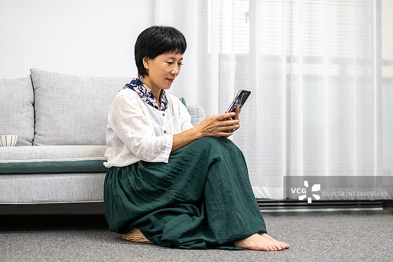 中年女人在家查看手机图片素材