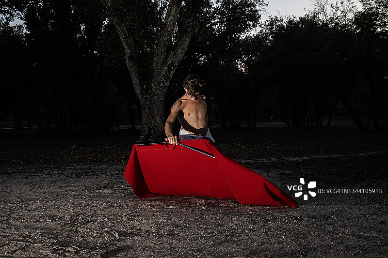 月光下完成训练的年轻赤膊斗牛士，手持斗篷和长剑图片素材