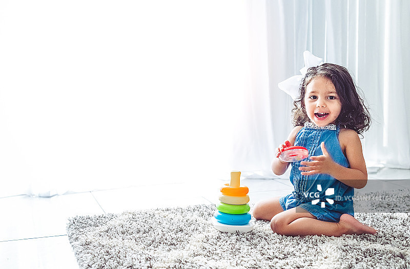 快乐的小女孩在客厅玩叠叠乐玩具图片素材