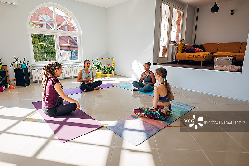 在专业瑜伽教练的指导下，练习冥想的女性群体图片素材