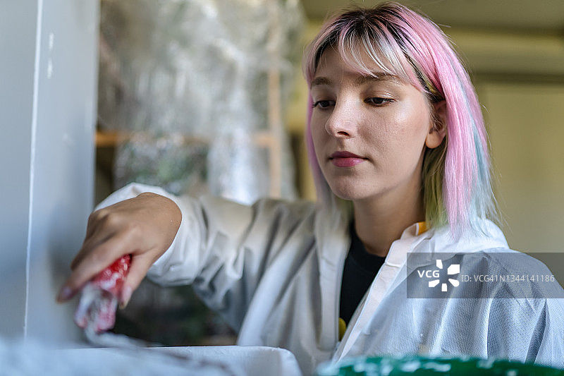 年轻女子在家中将墙壁涂成白色图片素材