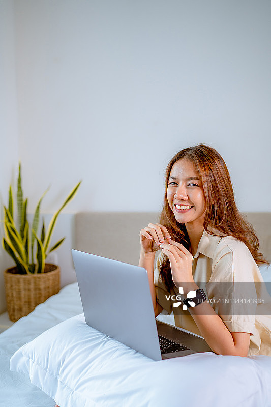 年轻美丽的商务女性居家办公，使用笔记本电脑图片素材